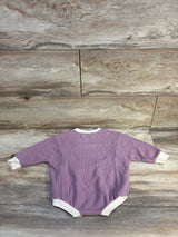 Purple ribbed baby onesie with white trim, laid flat on wood floor — kids clothing resale