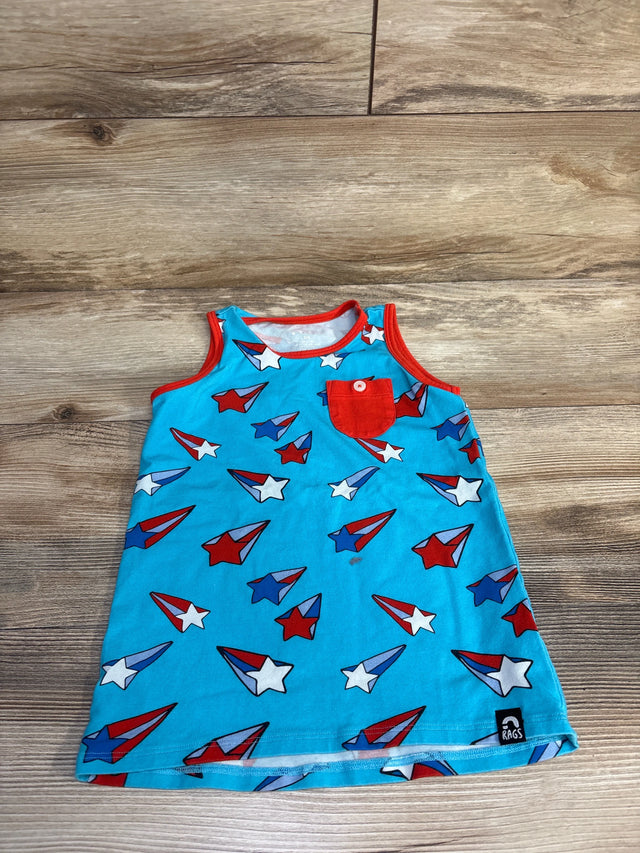 Flat lay of light-blue toddler tank top with red trim and pocket, red-white-blue star and airplane print on wood background
