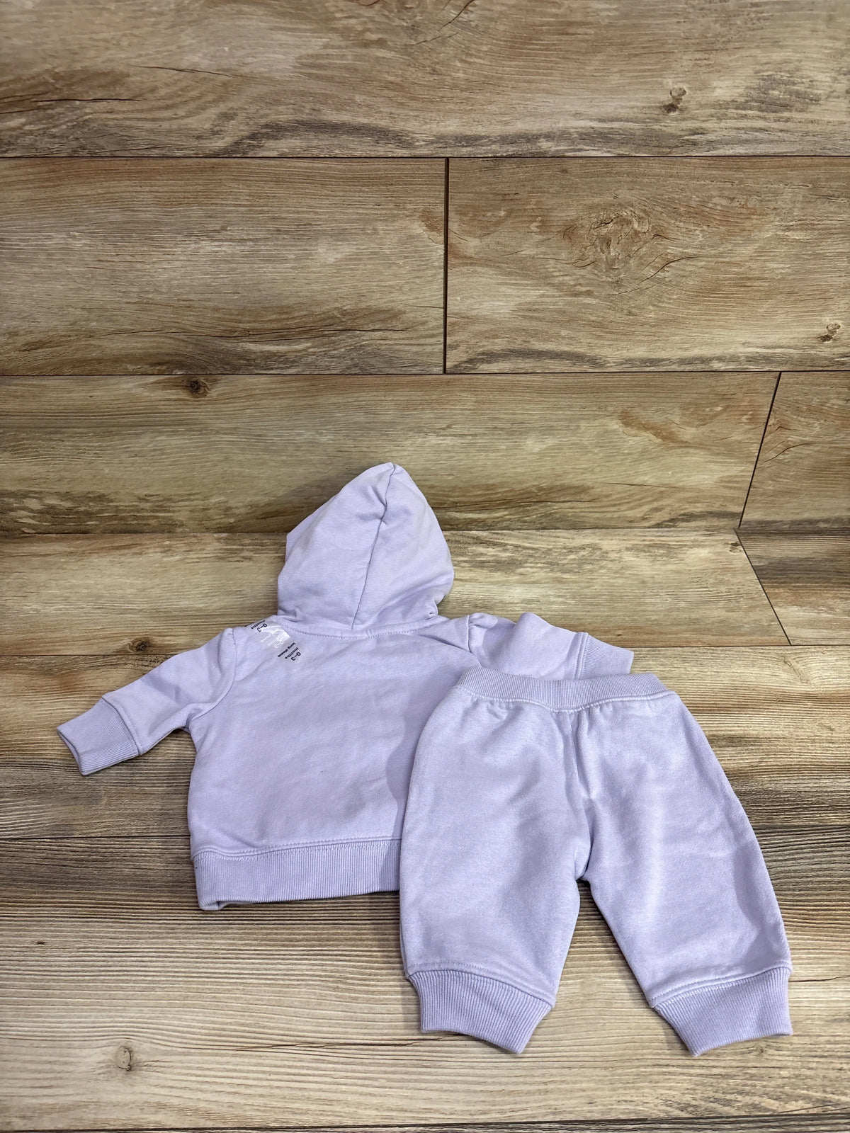 Baby Gap 2-piece lilac zip-up hooded jacket and joggers set for 0-3 months on a wood background