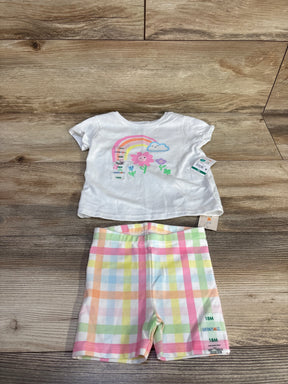 Flat lay of Garanimals 2-piece baby set size 18M: white tee with rainbow flower graphic and plaid shorts on wood background