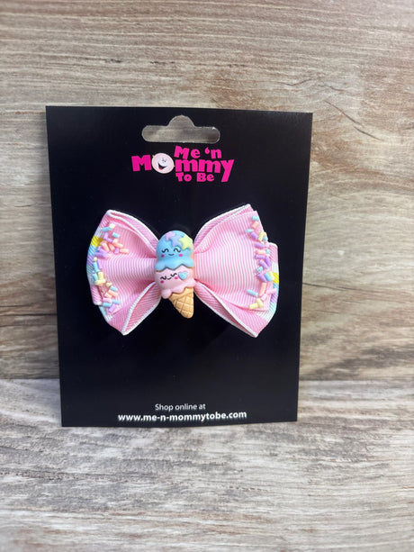 Front view of pink ribbon hair bow with smiling two-scoop ice cream applique and pastel sprinkle accents on a black display card