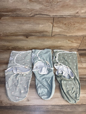 Three pastel baby swaddle blankets with animal and moon prints on wood floor