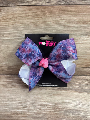 Front view of large hair bow in galaxy purple showing pink center knot and white loops on a black card over wood background
