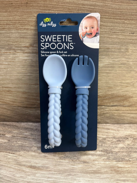 Front view of Sweetie Spoons silicone spoon and fork set in light and dark blue with braided handles on wood background