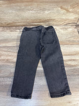 Black denim kids jeans with elastic waistband and back pocket, laid flat on wood floor
