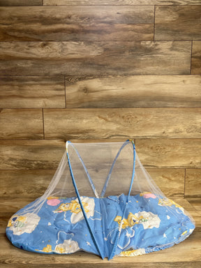 Blue baby mattress with cartoon bear print and protective white mesh netting on wooden floor
