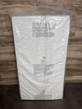 Top view of NEW Serta Perfect Slumber Dual Sided Crib and Toddler Mattress in white sealed plastic packaging on a wood plank background