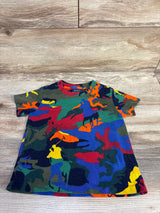 Flat-lay of toddler Polo Ralph Lauren short-sleeve shirt showcasing multicolor camo with polo player silhouettes, size 3T on light wood floor