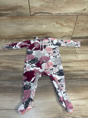 Floral baby onesie with pink, red, and black roses on white, laid on wood floor