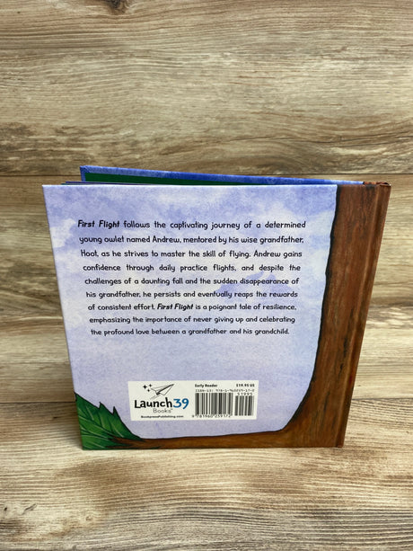 Back cover of children's book First Flight with story synopsis, barcode, and Launch39 Books logo on wood surface