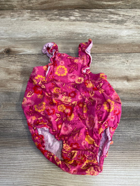 Flat-lay of pink floral baby bubble romper showing ruffle shoulder straps and snap crotch on wood background