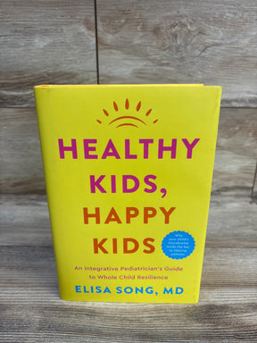 Front view of Healthy Kids, Happy Kids hardcover showing bright yellow cover with pink-orange title on wood background