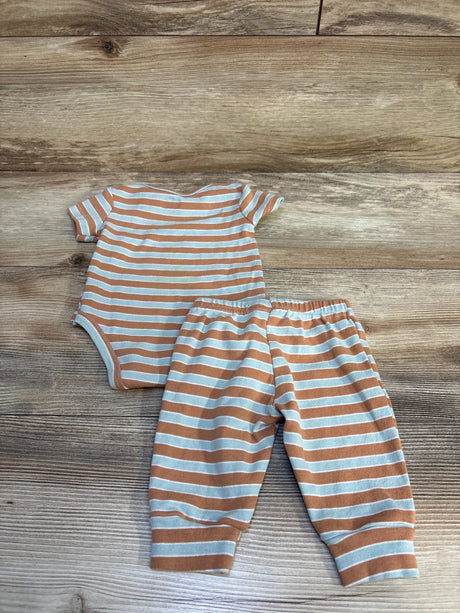 Striped baby bodysuit and pants set, orange and white, on wooden background