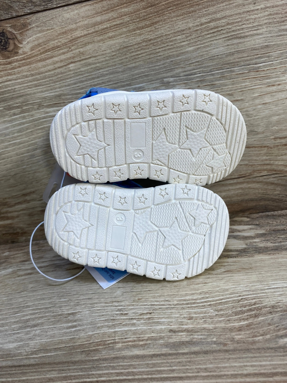 Pair of toddler shoes with white star-patterned soles on wood surface