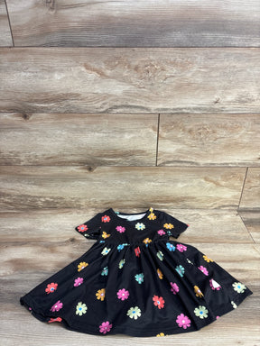Flat lay of black toddler short-sleeve dress with colorful daisy print and gathered waist, size 12-18 months, on light wood floor
