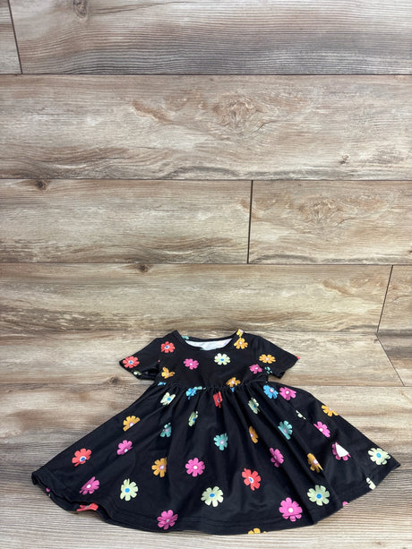 Flat lay of black toddler short-sleeve dress with colorful daisy print and gathered waist, size 12-18 months, on light wood floor
