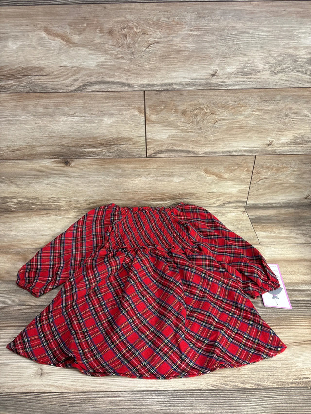 Red plaid kids dress with ruffled waist, laid on wood floor, resale clothing
