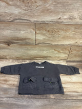 Front view of Zara Explore Now grey sweatshirt, size 3 to 6 months, with two flap pockets and ribbed trim on wood planks