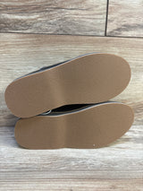 Pair of kids shoes with clean brown rubber soles on wood background