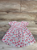 Flat lay of girls' pink floral dress size 4T showing short sleeves, gathered waist, and rose print on wood floor background