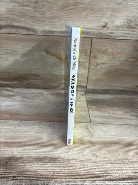 Spine view of Nature’s Children: Squirrels & Frogs hardcover book showcasing the title on a white spine with a wood-look background