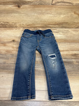 Kids' distressed denim jeans with ripped knee, laid on wooden floor