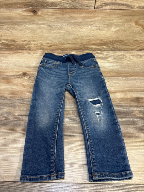 Kids' distressed denim jeans with ripped knee, laid on wooden floor