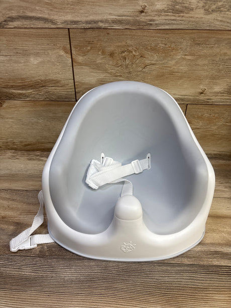 Front view of JoolBaby Booster Floor Seat showcasing molded contours and a white safety harness on a wood floor