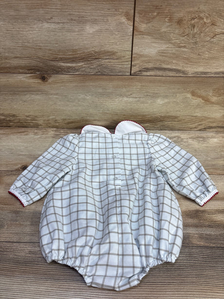 Front view of white Peter Pan collar bubble romper with gray plaid, long sleeves, buttons, and red trim on wood background