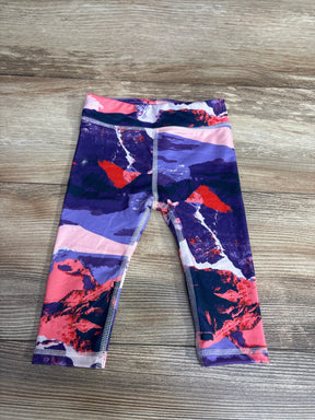 Colorful baby leggings with purple, pink, and red abstract pattern on wood background