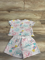 Flat lay of grey PAW Patrol two-piece shirt and shorts showing multicolor character and paw-print pattern on wood background