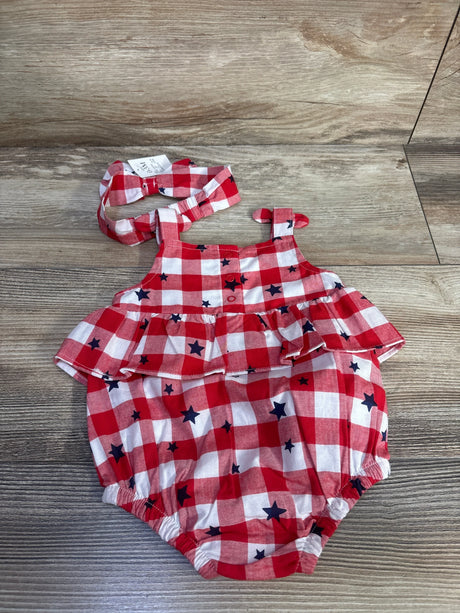 Flat lay of red gingham bubble romper with navy stars and matching headband showing ruffle yoke and elastic leg openings on wood background