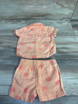 Flat lay of 2-piece palm tree button-up shirt and elastic-waist shorts showcasing coral fabric with pink palm tree print on wood background