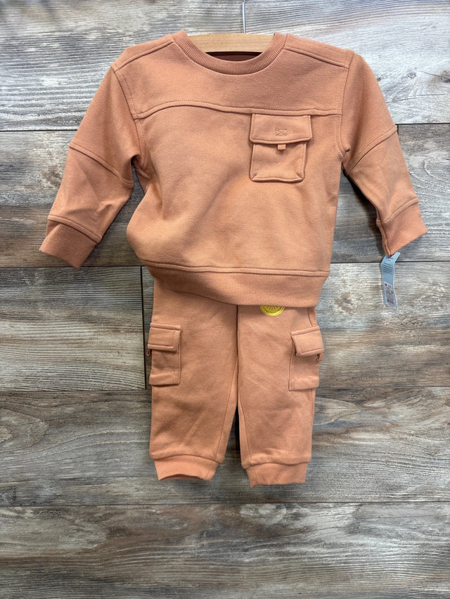 Rust orange toddler sweatshirt and jogger pants set with pockets, displayed on wooden background.