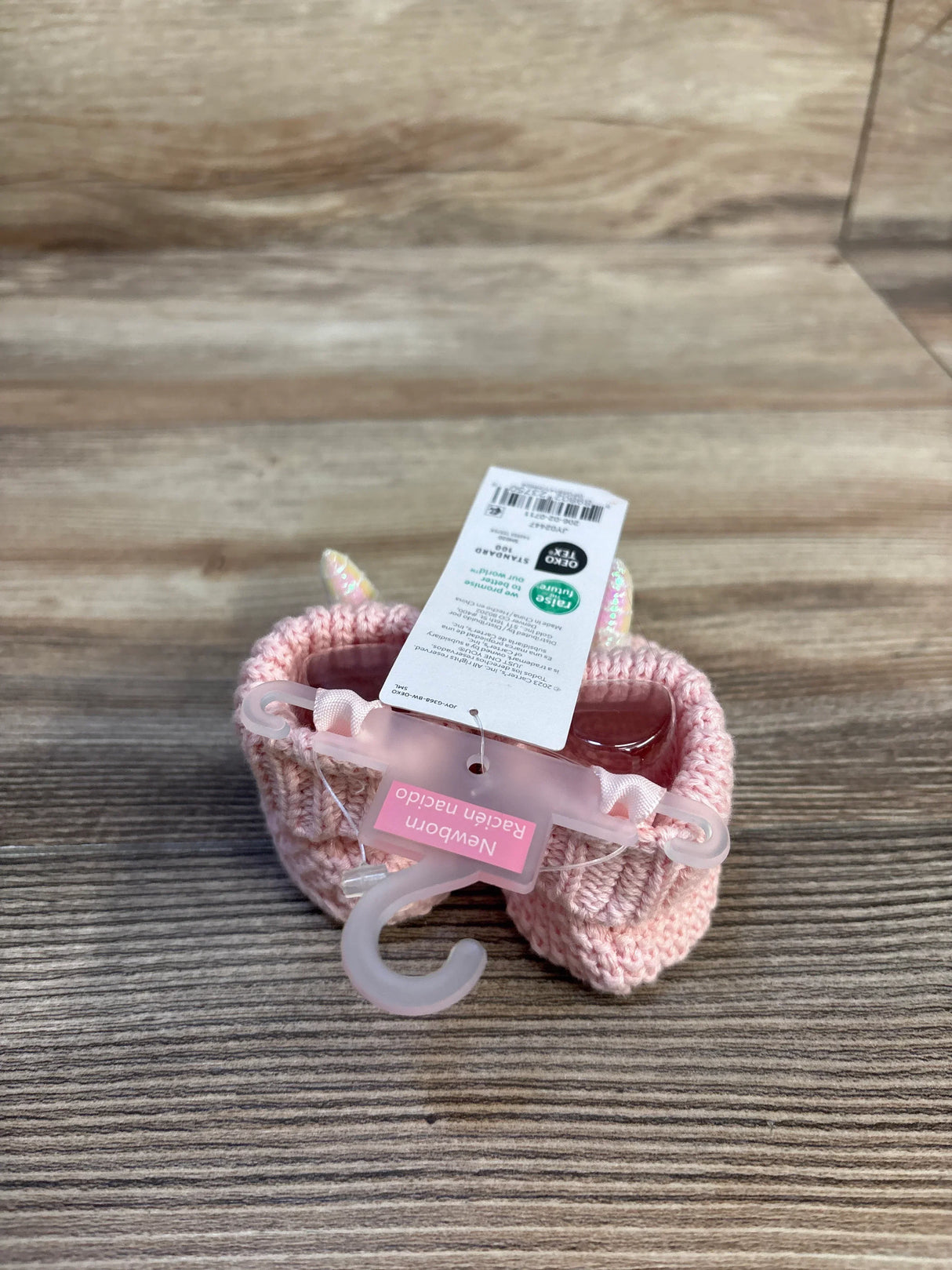 Pink knitted newborn booties with unicorn horns, perfect for baby gear and maternity outfits.