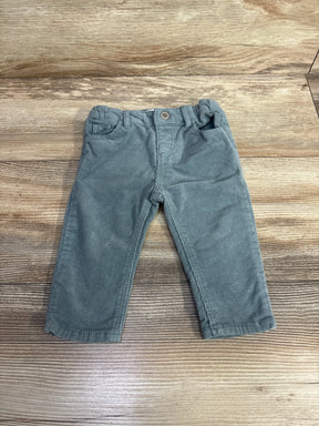 Gray corduroy toddler pants with pockets and button closure on wood background