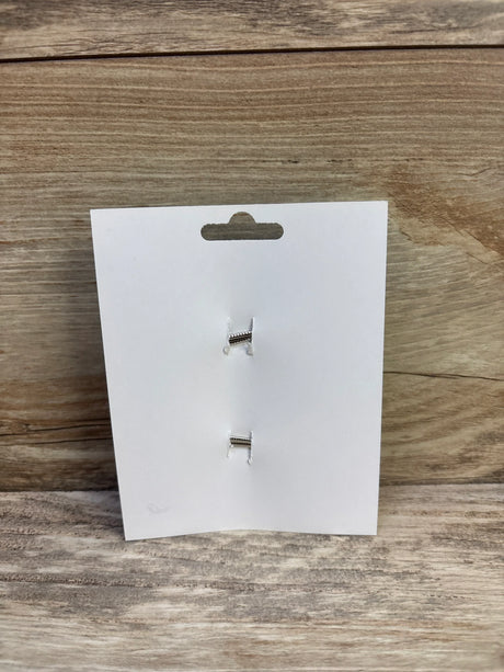Front view of two small blue hair bows clipped to a white display card on a wood surface