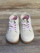 Light pink toddler shoes with pink laces on wood background, baby footwear