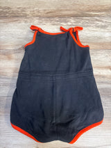 Black baby romper with red trim and shoulder ties on wooden background