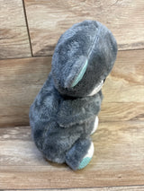 Gray plush stuffed animal toy with teal ear detail, sitting on wood floor