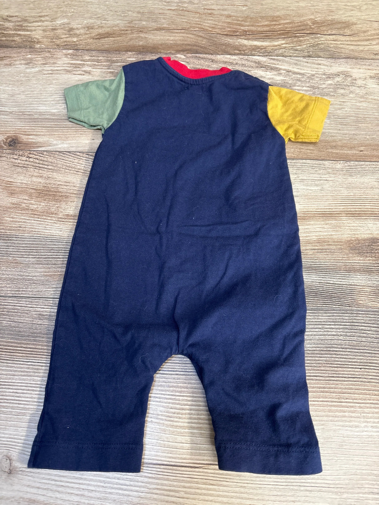 Navy blue baby romper with green and yellow short sleeves on wood background