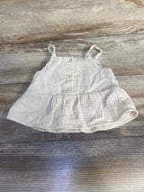 Flat lay of ivory peplum tank top (24 months) showing front buttons, ruffled hem and crochet straps on wood background