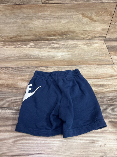Front view of blue Nike cotton shorts in size 2T, showcasing an elastic waistband and Nike swoosh on a wood-grain background