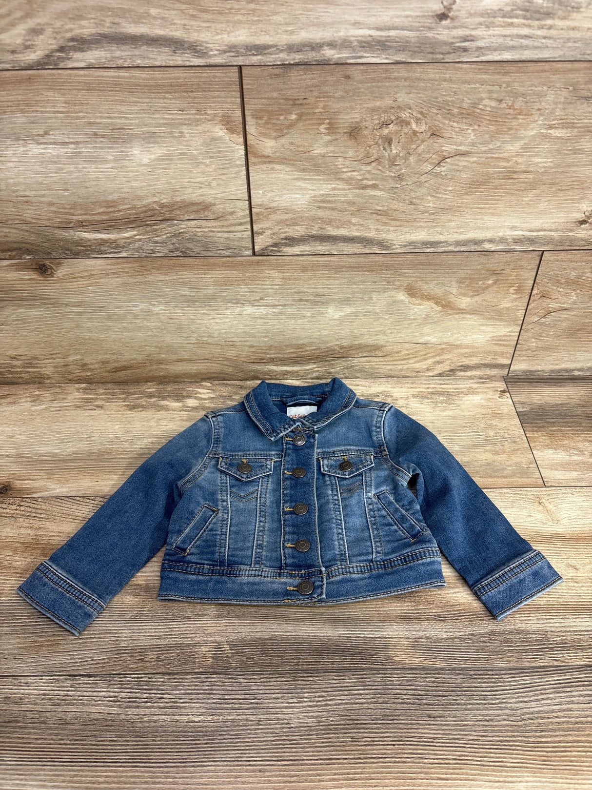 Blue denim toddler jacket with button front and pockets on wood background