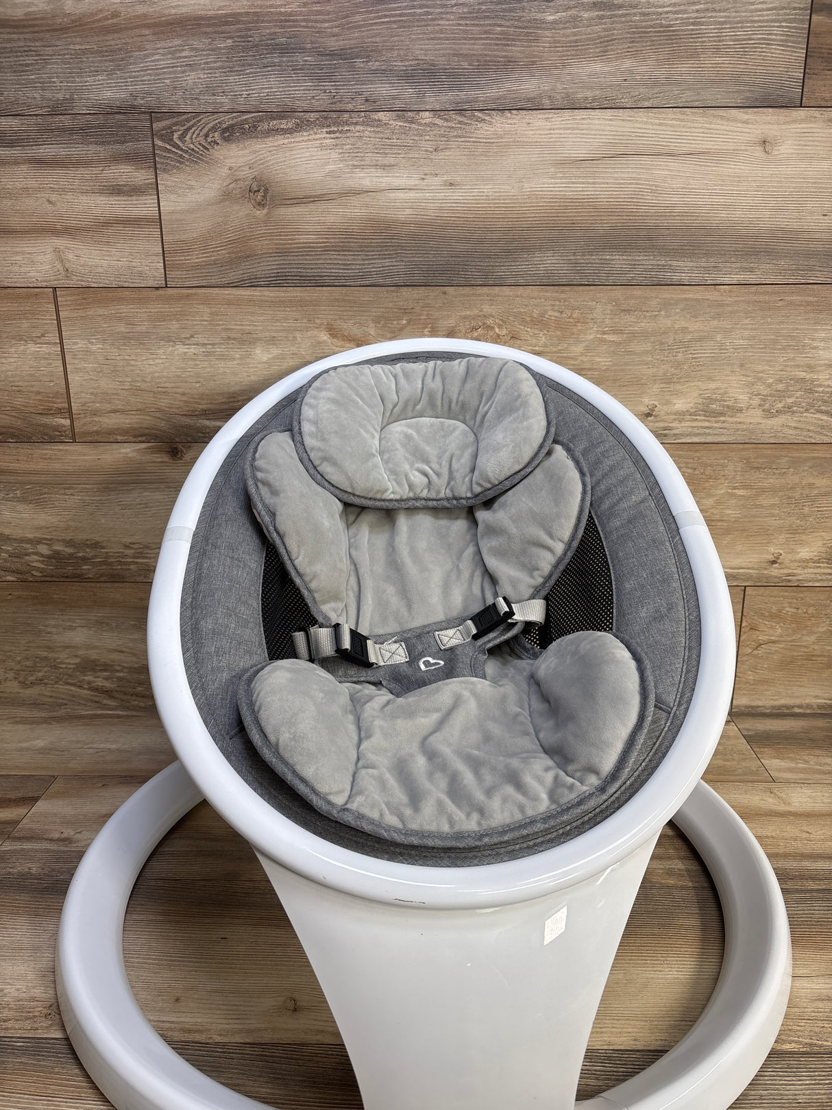 Top-down view of Munchkin Bluetooth-enabled baby swing showing gray padded infant seat and harness on white circular base