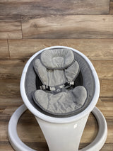 Top-down view of Munchkin Bluetooth-enabled baby swing showing gray padded infant seat and harness on white circular base