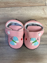 Top-down of pink toddler PU leather walking sneakers size 3 showing butterfly appliqué, Velcro strap, and black scalloped sole on wood