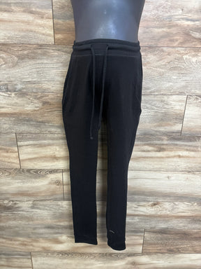 Front view of black drawstring maternity joggers showing waistband and tapered legs on wood plank background