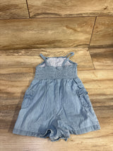 Front flat lay of blue chambray romper (18M) showing smocked bodice, thin straps, side pockets on wood floor