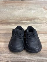 Front view of Nike Air Force 1 crib shoes showing black leather upper and laces on a wood plank background